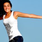 A joyful woman jumping on a beach with arms outstretched, symbolizing emotional freedom and well-being, aligning with the concept of understanding EMDR therapy.