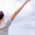 A woman standing in a field with her arms raised, symbolizing freedom and personal growth. The image represents recovery from codependency and addiction, highlighting empowerment, healing, and a fresh start toward emotional independence.