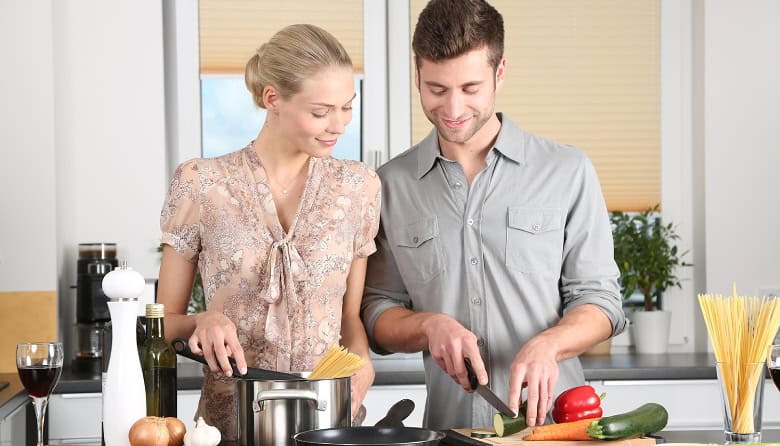 Smiling couple cooking together in a modern kitchen, demonstrating teamwork and positive communication in marriage. Smiling couple cooking together in a modern kitchen, demonstrating teamwork and positive communication in marriage.