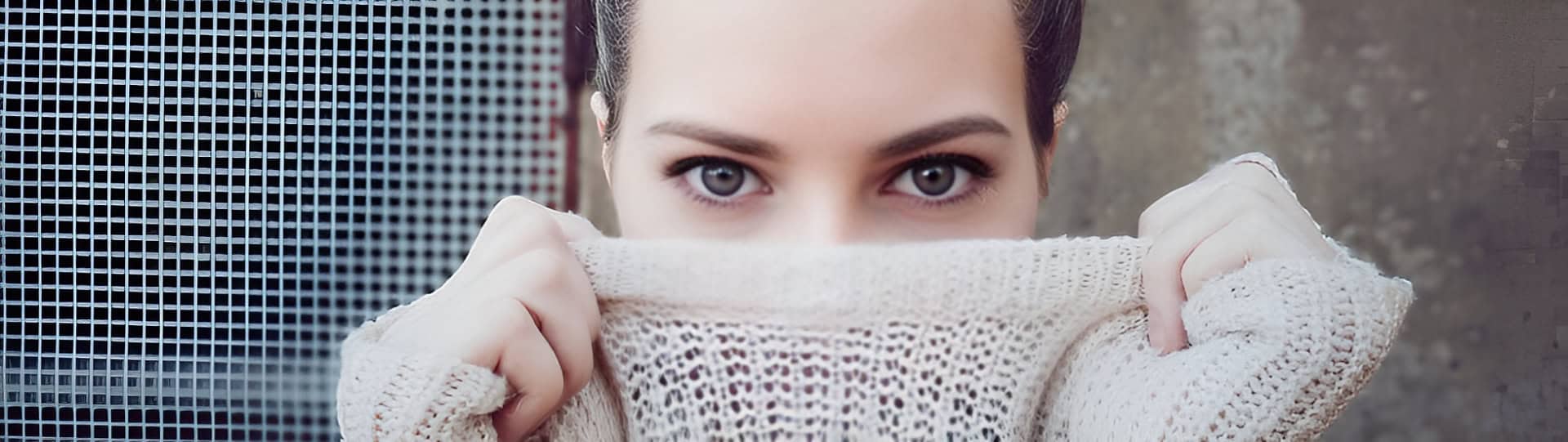 Close-up of a woman partially hiding her face with a sweater, representing emotional vulnerability addressed through EMDR therapy for trauma and PTSD.