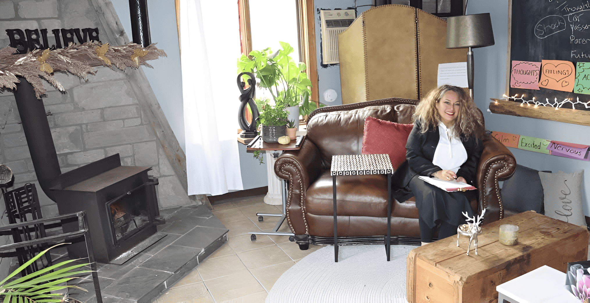 Gloria Segovia sitting in the cozy AERCS therapy cabin in Orangeville, surrounded by warm décor, a fireplace, and inspirational messages, offering a glimpse into the comforting space behind the question: what is AERCS?