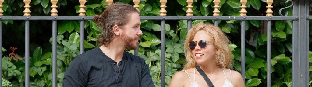 Couple sitting by a park fence having an open conversation, representing relationship healing and the role of infidelity counselling in rebuilding trust.