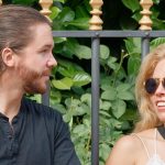 Couple sitting by a park fence having an open conversation, representing relationship healing and the role of infidelity counselling in rebuilding trust.
