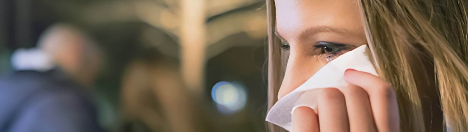A close-up of a distressed woman wiping away tears in a dimly lit setting, symbolizing emotional pain often addressed in infidelity counselling.