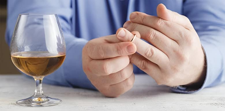 A man sits with a glass of alcohol, pausing as he either removes or puts on his wedding ring, capturing the emotional complexity often addressed in infidelity counselling. A man sits with a glass of alcohol, pausing as he either removes or puts on his wedding ring, capturing the emotional complexity often addressed in infidelity counselling.