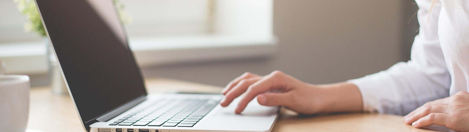 Person using a laptop in a bright workspace, representing practical self care strategies for a busy workday.