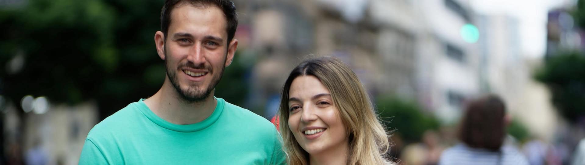 A smiling couple standing close together on a busy city street, representing a positive relationship outcome after understanding and completing the full couples counselling duration.