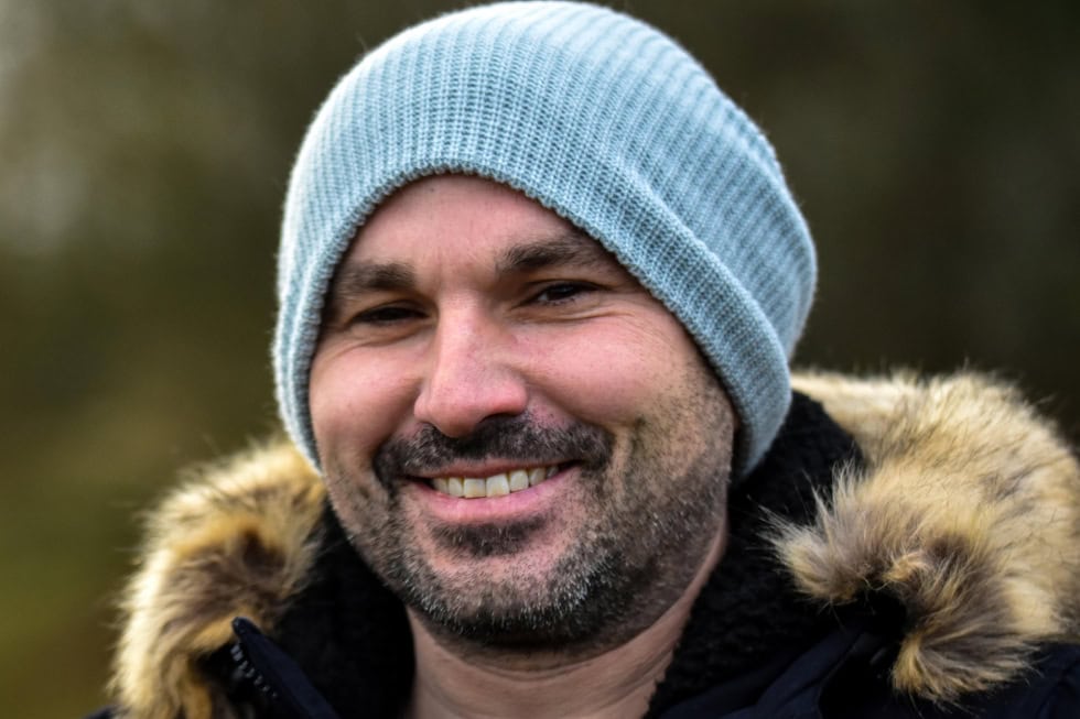 Smiling man in a winter jacket and knit hat outdoors, representing positive outcomes from EMDR for anxiety and stress.