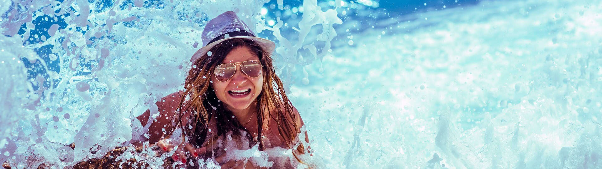 Woman caught in an ocean wave, expressing surprise and tension, symbolizing the sudden impact of panic attacks and the need for grounding and calming strategies.