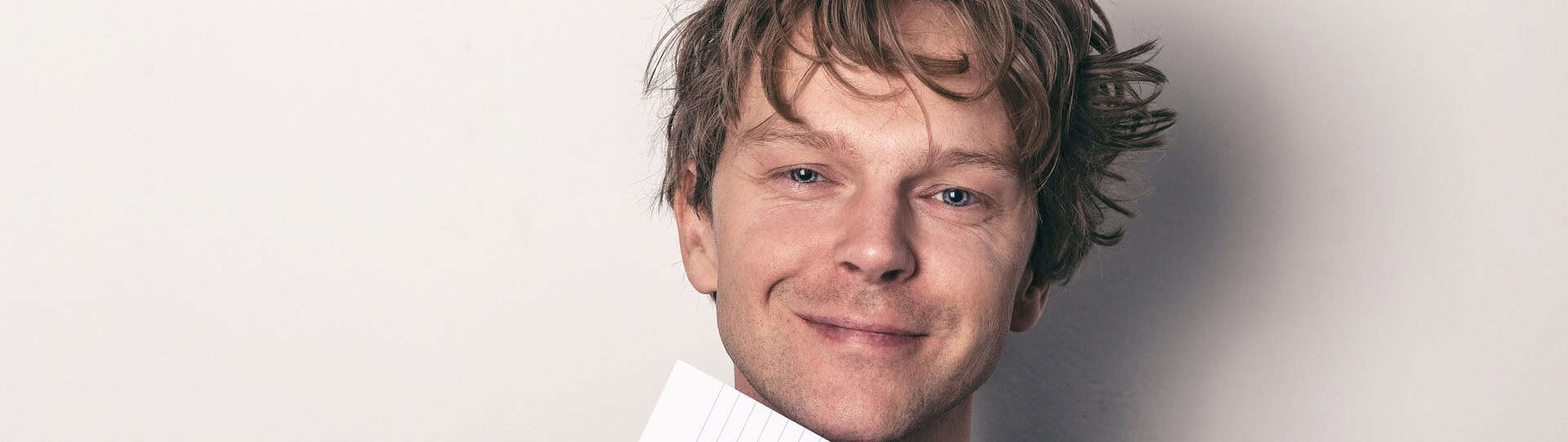 Smiling man holding a notepad, symbolizing positive progress and self-reflection while learning how to stop overthinking and manage anxious thoughts.