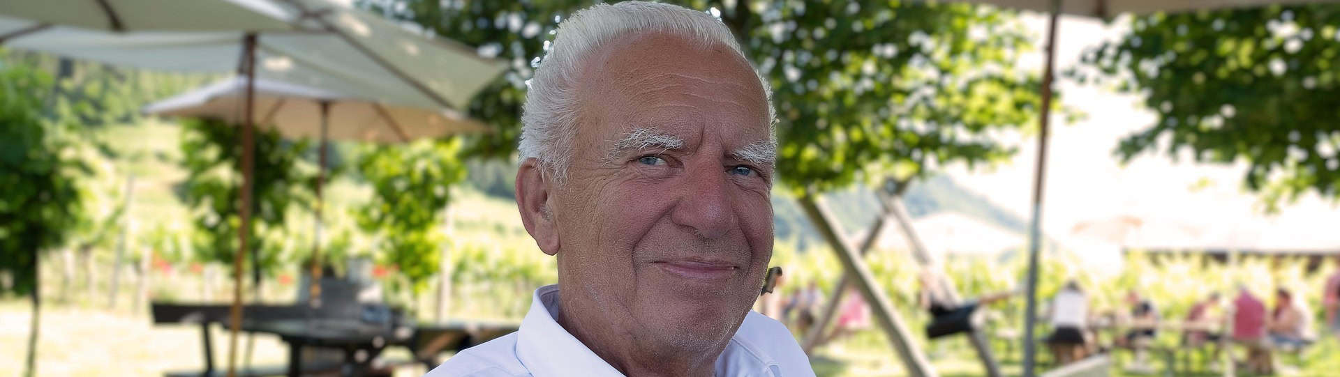 Older man sitting outdoors under shade, appearing calm and content, representing the use of grounding techniques to manage anxiety and stay present in the moment.