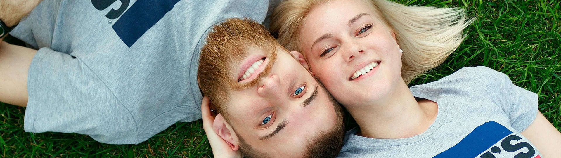 Smiling couple lying on grass, representing the balance of joint and individual sessions in couples therapy for stronger communication and connection.