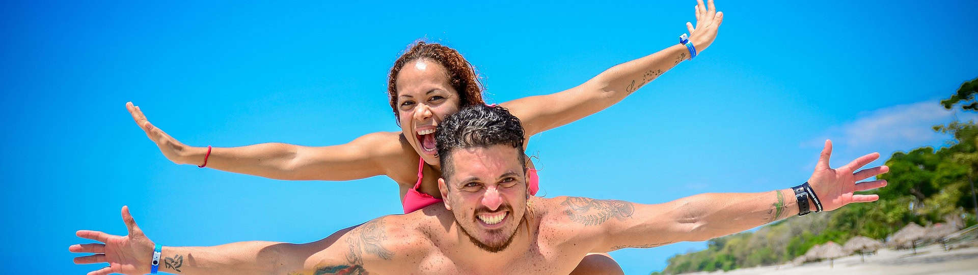 Smiling couple playing on the beach, symbolising restored connection and happiness after recognising that their relationship needs counselling.
