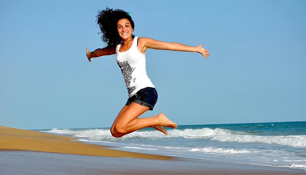 Woman joyfully jumping on a beach under a clear blue sky, representing freedom and emotional healing for the article on understanding EMDR therapy. Woman joyfully jumping on a beach under a clear blue sky, representing freedom and emotional healing for the article on understanding EMDR therapy.